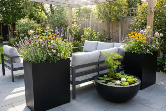 Three rectangular planters on a sunlit stone patio—one slatted wood, one rusted metal cube, and one long black trough